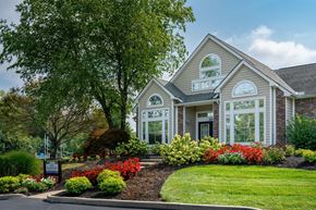 Florence townhouse for rent - Windridge leasing office exterior with a sign, plants, and large trees.