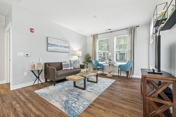 Indianapolis apartment for rent - A living room with a brown couch, blue chairs, and a painting on the wall.