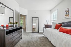 Indianapolis apartment for rent - A bedroom with a large bed and a dresser with a mirror above it.