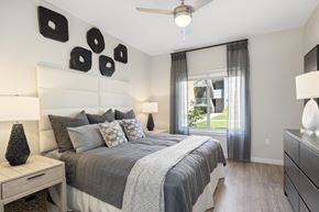 Tucson apartment for rent - A bedroom with a large bed, a ceiling fan, and a window with curtains.