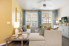 Marana apartment for rent - A living room with a beige sofa, a wooden coffee table, and a ceiling fan.