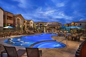 Marana apartment for rent - A swimming pool surrounded by chairs and umbrellas in a residential area.