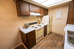 Tucson apartment for rent - A kitchen with a stove, refrigerator, and wooden cabinets.