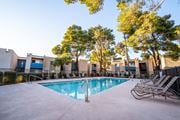 Tucson apartment for rent - A swimming pool surrounded by trees and chairs in front of a building.