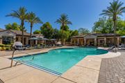 Goodyear apartment for rent - A swimming pool surrounded by palm trees and lounge chairs.