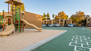 Tucson apartment for rent - A playground with a slide and a hopscotch board painted on the ground.