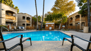 Tucson apartment for rent - A pool surrounded by a fence and chairs with a building in the background.