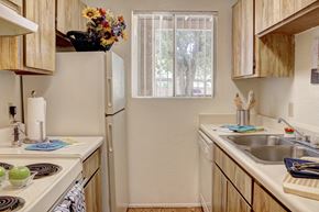 Tucson apartment for rent - Apartment kitchen with wooden cabinets and a white refrigerator.