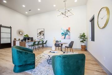 Tucson apartment for rent - A living room with a green chair in the foreground and a dining area in the background.