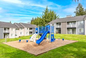 Olympia apartment for rent - A playground with a blue slide and white slide in the middle of a sandy area.