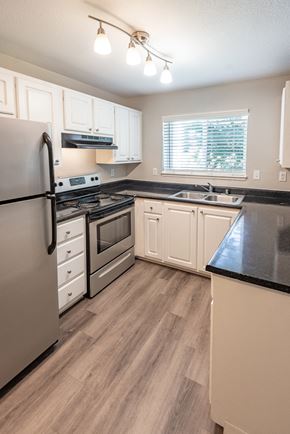 Olympia apartment for rent - a kitchen with white cabinets and black countertops