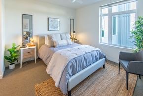 Kent apartment for rent - A bedroom with a large bed, a chair, and a potted plant.