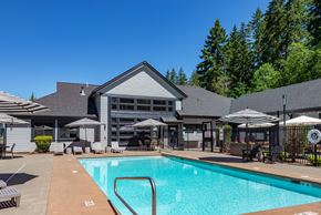 Bonney Lake apartment for rent - A large swimming pool in front of a house with a patio and umbrellas.