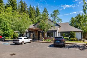 Bonney Lake apartment for rent - A white car is parked in front of a building with a black car parked behind it.