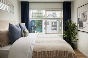 Puyallup townhouse for rent - A bedroom with a large bed and a view of a blue house through the window.