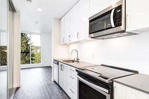 Redmond townhouse for rent - a kitchen with white cabinets and a stove and a microwave