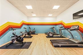 Lynnwood apartment for rent - a gym with treadmills and exercise bikes and a wall with a rainbow mural