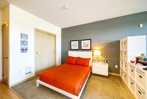 Seattle apartment for rent - a bedroom with an orange bed and white cabinets