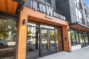 Seattle apartment for rent - the front of a building with glass doors and a sign on the side of it