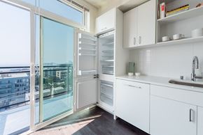 Seattle apartment for rent - a kitchen with white cabinets and a sliding glass door that leads to a balcony