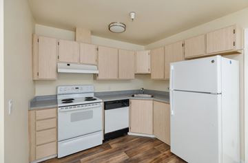 Burien apartment for rent - A kitchen with white appliances and wooden cabinets.