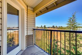 Vancouver apartment for rent - A balcony with a black railing and a view of a field and trees.