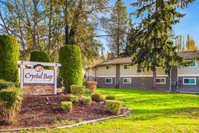 Des Moines apartment for rent - A sign for Crystal Bay is surrounded by shrubbery and trees.