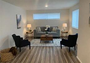 Tacoma apartment for rent - A living room with a grey couch, two black chairs, and a coffee table.