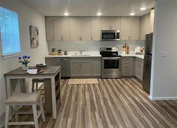Tacoma apartment for rent - A kitchen with wooden floors and a table with a vase of flowers on it.