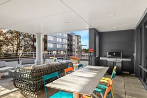 Seattle apartment for rent - A modern outdoor dining area with a long table surrounded by colorful chairs.