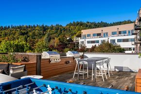 Portland apartment for rent - A blue hot tub sits on a wooden deck with a white table and chairs.