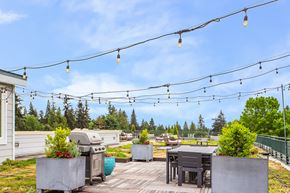 Seattle apartment for rent - the patio has a grill and tables and chairs and a view of the trees