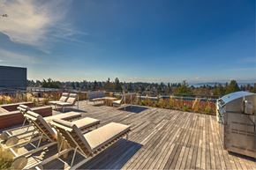 Seattle apartment for rent - a deck with chairs and a grill on top of a roof