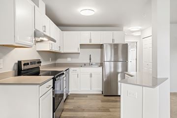 Seatac apartment for rent - A modern kitchen with white cabinets and stainless steel appliances.