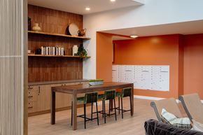 Shoreline apartment for rent - A kitchen with a table and chairs in the foreground and a calendar on the wall in the background.