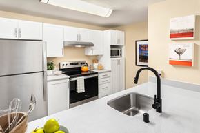 Lynnwood apartment for rent - a kitchen with white cabinets and a sink and a refrigerator