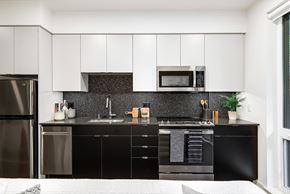 Seattle apartment for rent - a modern kitchen with black and white cabinets and stainless steel appliances