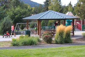 Bend apartment for rent - A man is standing on a swing set at a playground.