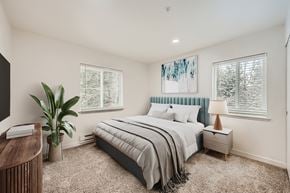 Olympia apartment for rent - A bedroom with a large bed, a nightstand with a lamp, and a plant.