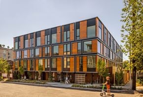 Seattle apartment for rent - a large building with many windows and a child on a scooter
