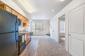 Seattle apartment for rent - a renovated kitchen with black appliances and wooden cabinets and a door to a living room