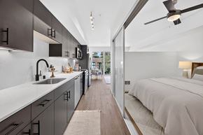 Seattle apartment for rent - A modern kitchen with a long counter and a bedroom with a bed and a nightstand.