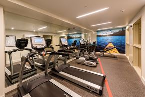 Kirkland apartment for rent - a gym with cardio equipment and a mural of a mountain and lake