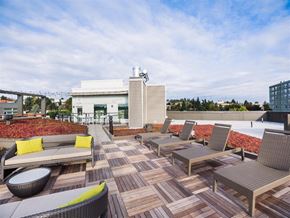 Seattle apartment for rent - A patio with a white couch and chairs with a building in the background.