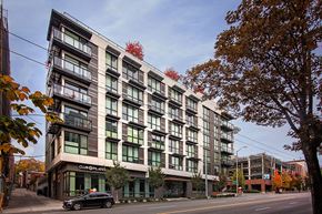 Seattle apartment for rent - a large white building with green windows and a black car parked in front of it