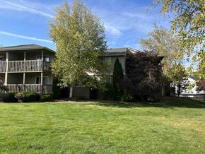 Bend apartment for rent - A grassy area in front of a two-story house with a tree in the foreground.