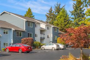 Burien apartment for rent - A red car is parked in front of a blue building.
