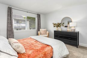 Burien apartment for rent - A bedroom with a bed, nightstand, and chair.