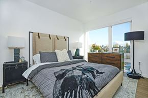Seattle apartment for rent - A bedroom with a large bed and a view of trees outside the window.