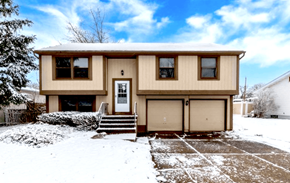 Amherst townhouse for rent - A beige house with a white door and windows is surrounded by snow.